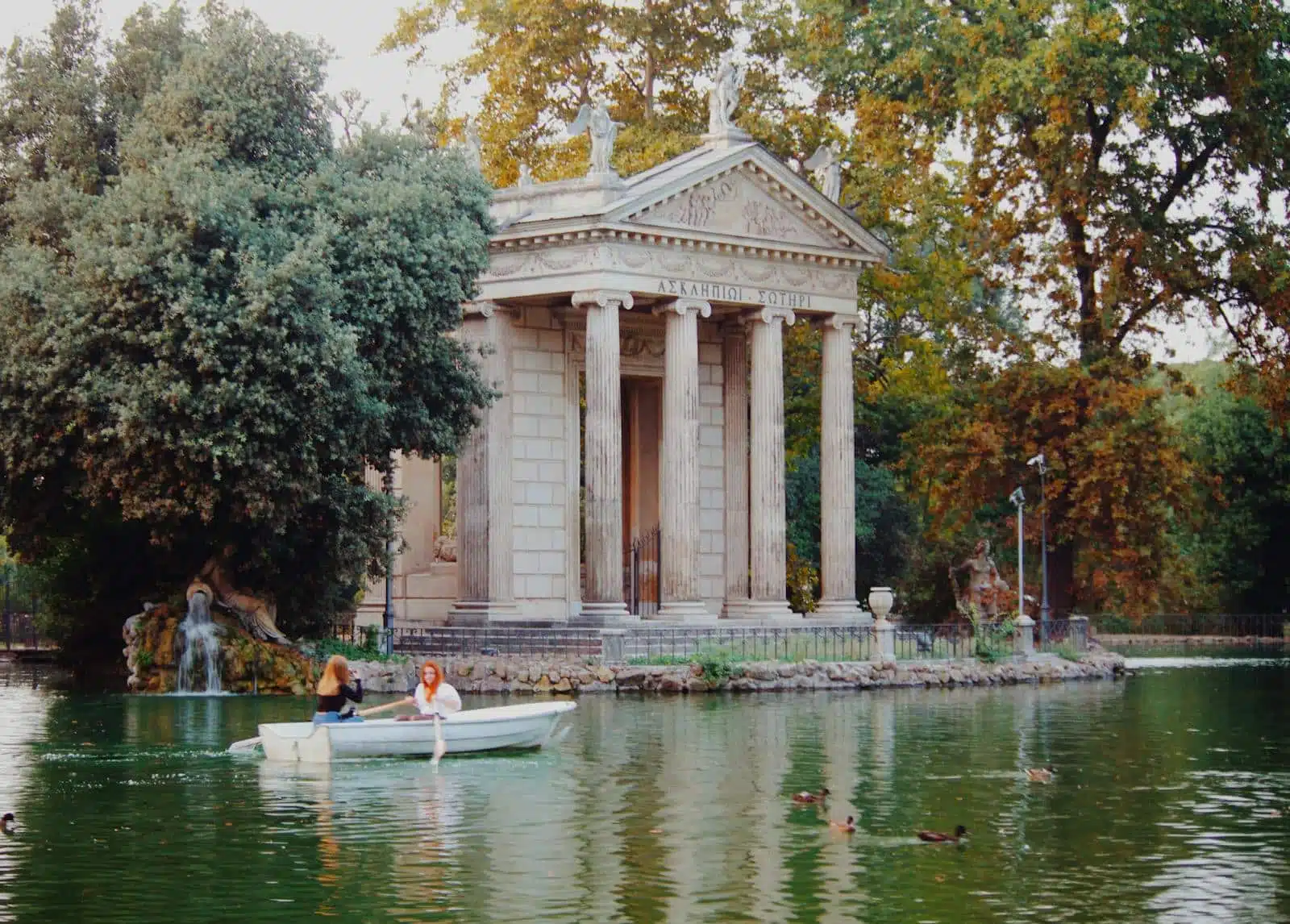 Villa Borghese A serene canal scene with a boat navigating by an ancient temple in Rome's Villa Borghese.