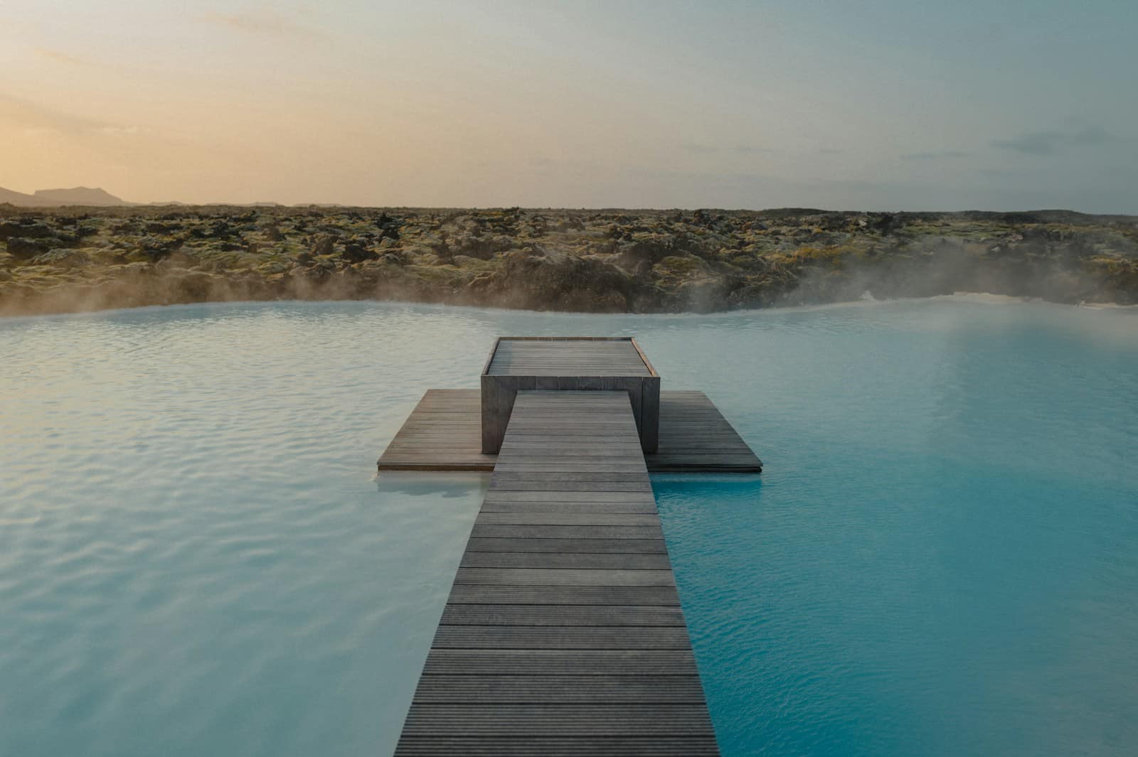 a wooden dock leading to a blue lagoon