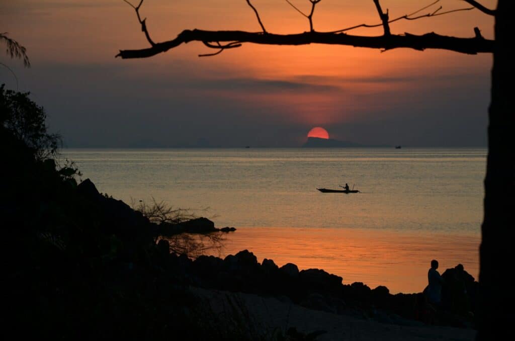 silhouette of person riding on boat on sea during sunset