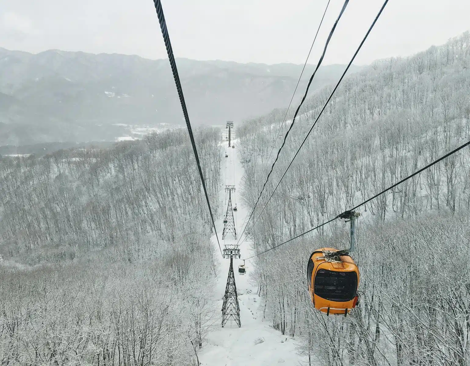 Cable car journey over snow-covered forests in Hakuba, Nagano, Japan, during winter.