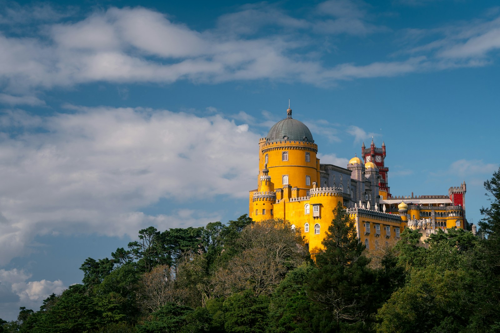 A large yellow castle sitting on top of a lush green hillside