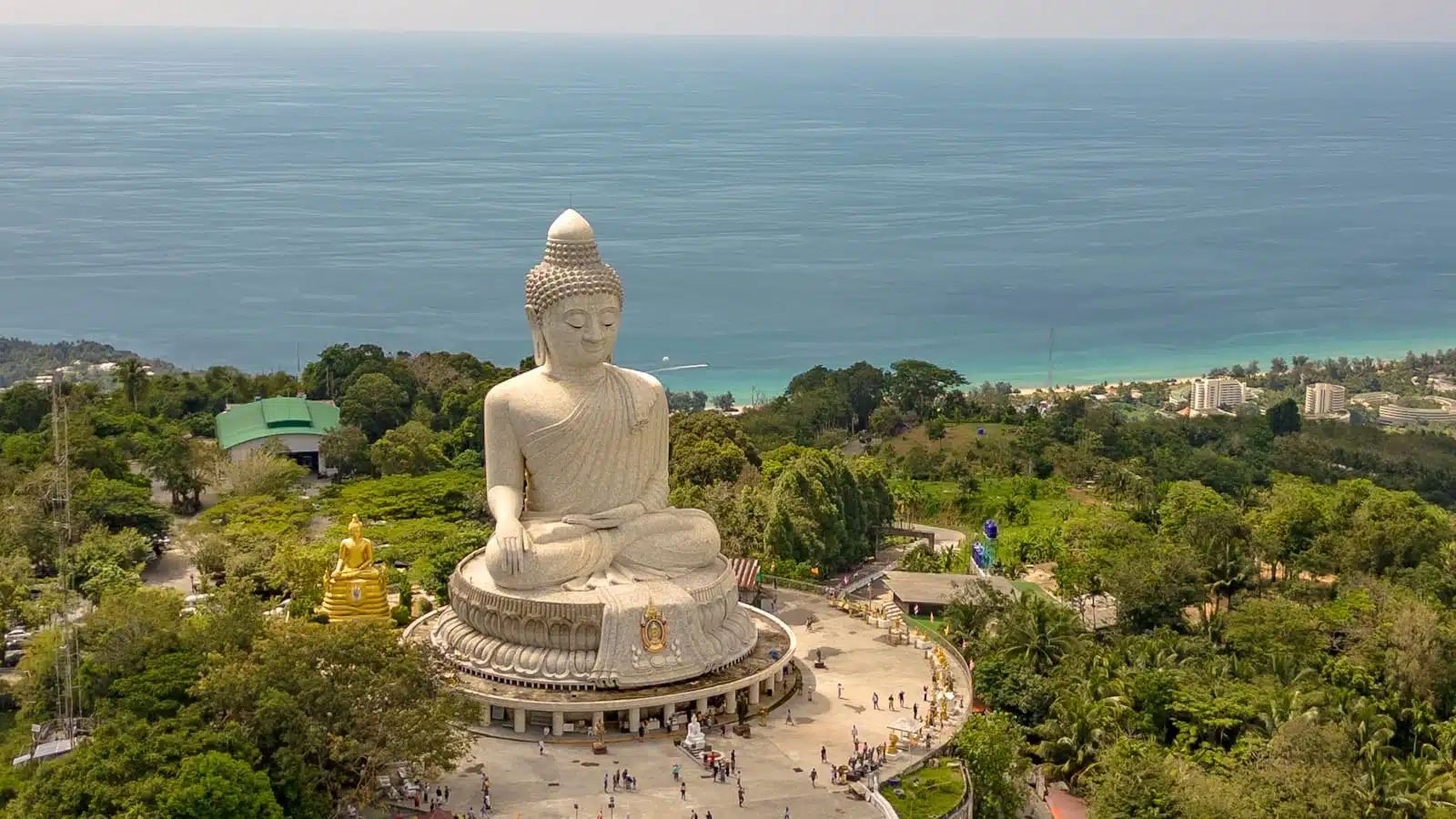 Large white buddha statue overlooking ocean and coastline