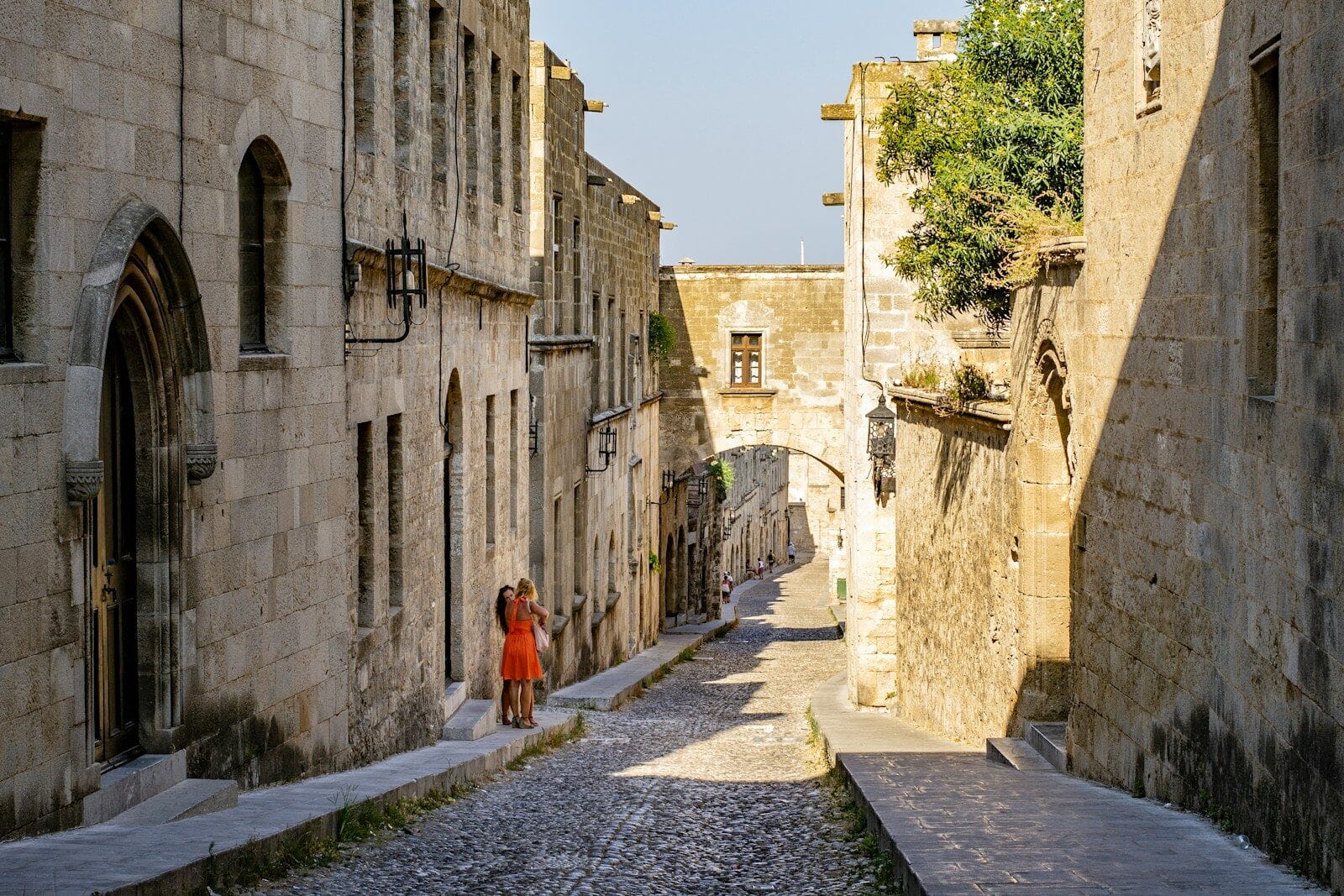 woman in orange dress walking on gray concrete pathway during daytime
