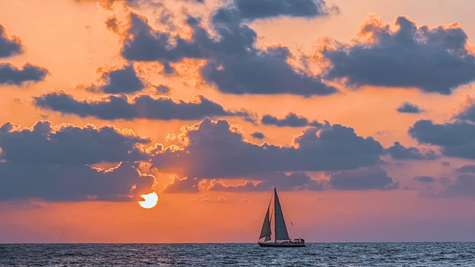 A sailboat in the ocean at sunset