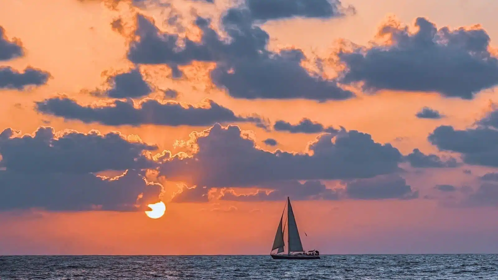 A sailboat in the ocean at sunset