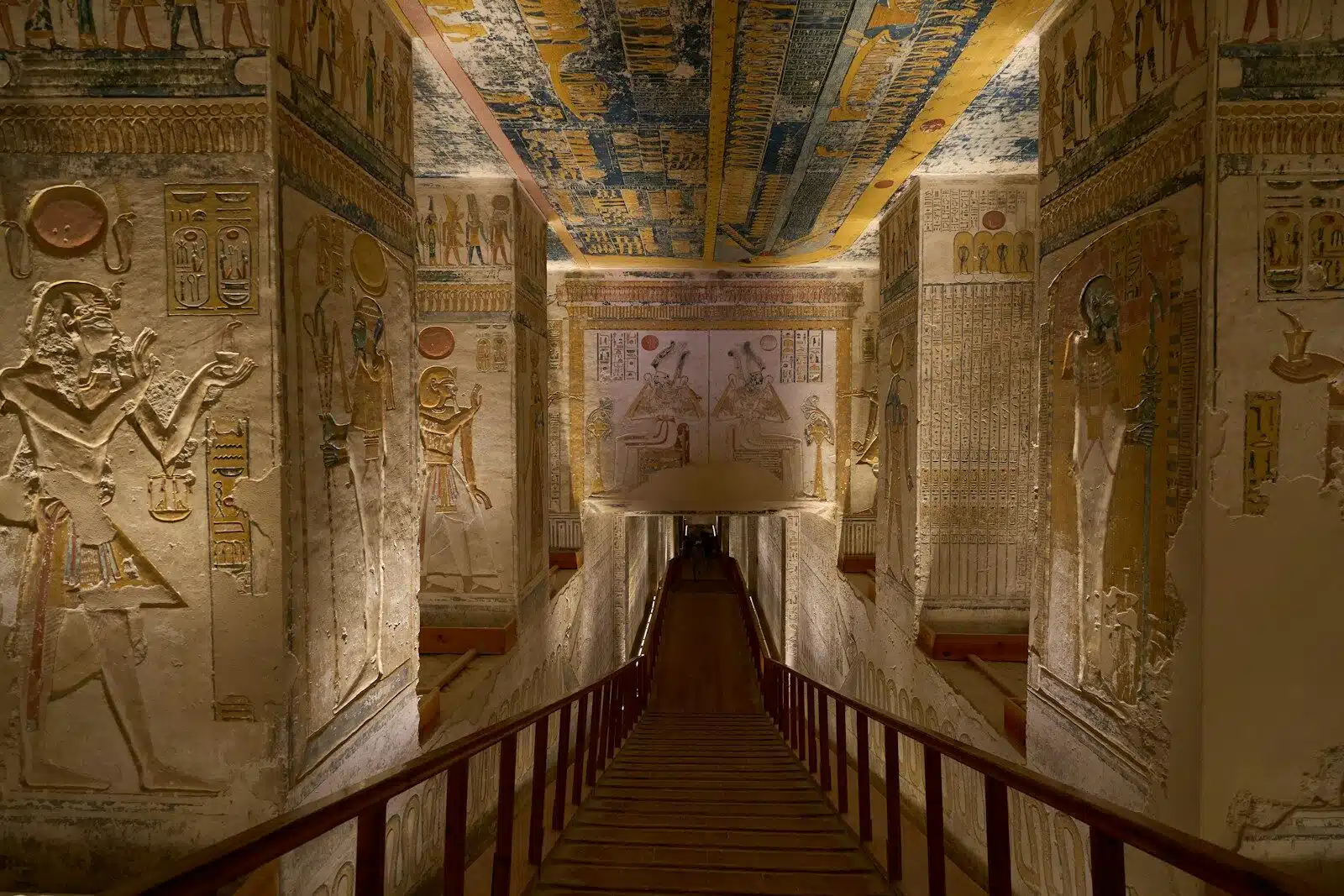 A stone staircase descending into an ancient Egyptian tomb with painted hieroglyphic walls, valley of the kings tour
