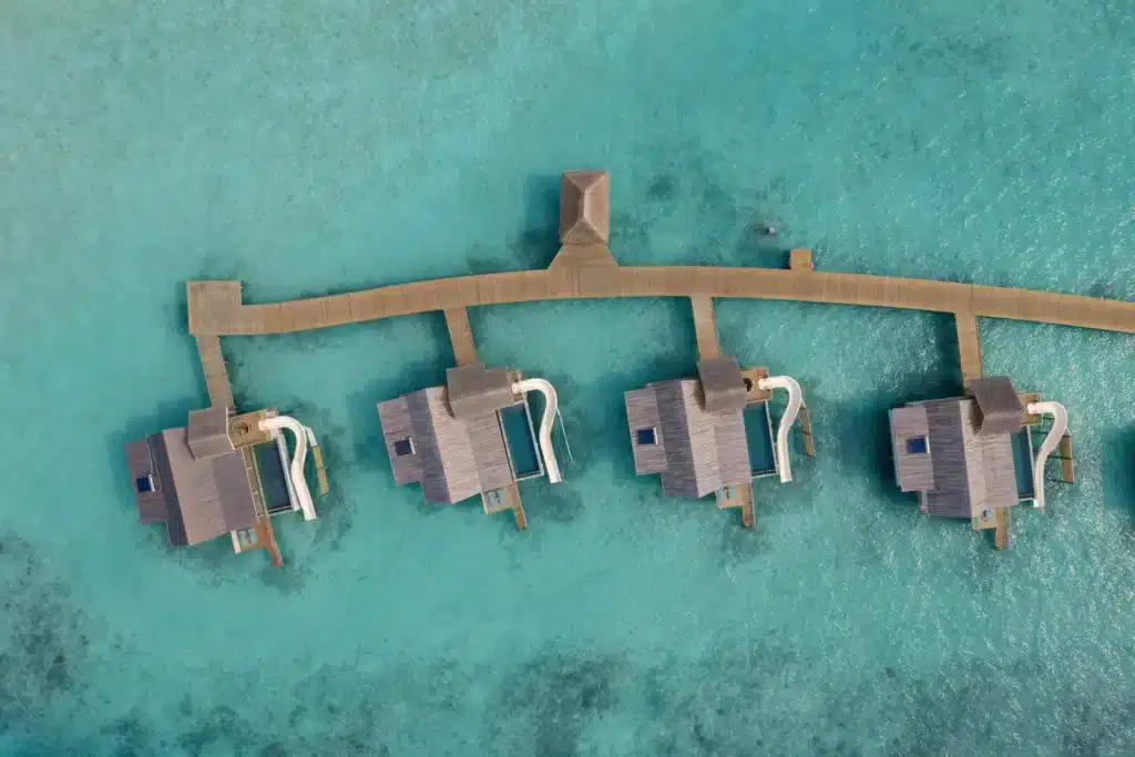 Aerial view of overwater villas with pool slides at Rah Gili Maldives