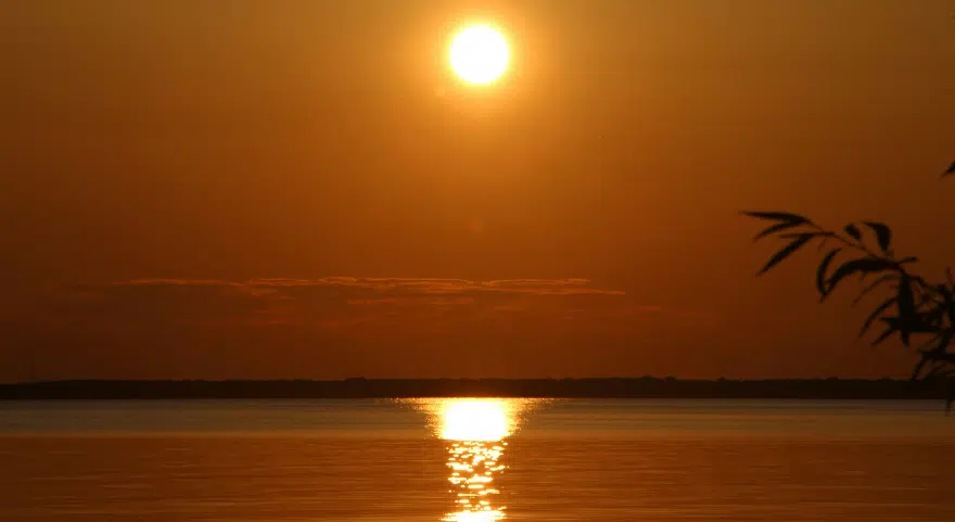 The sun sets over the Mekong River near Phnom Penh, reflected in the still water.