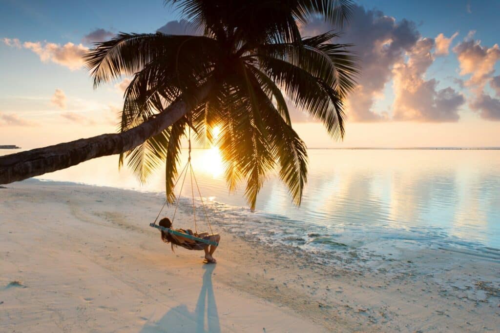 Palm tree swing on a beach in the Maldives at sunset