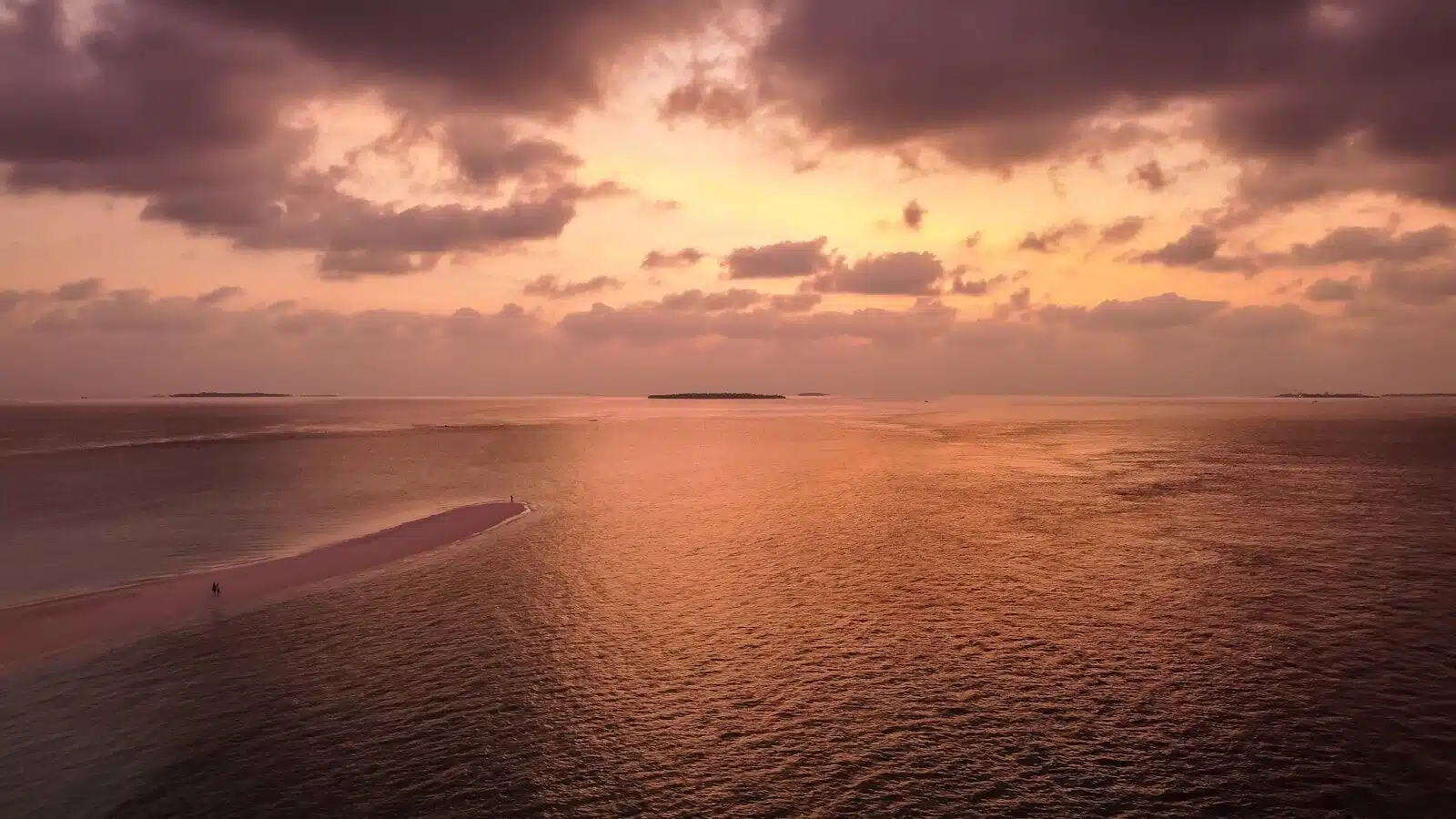 the sun is setting over the ocean with clouds in the sky