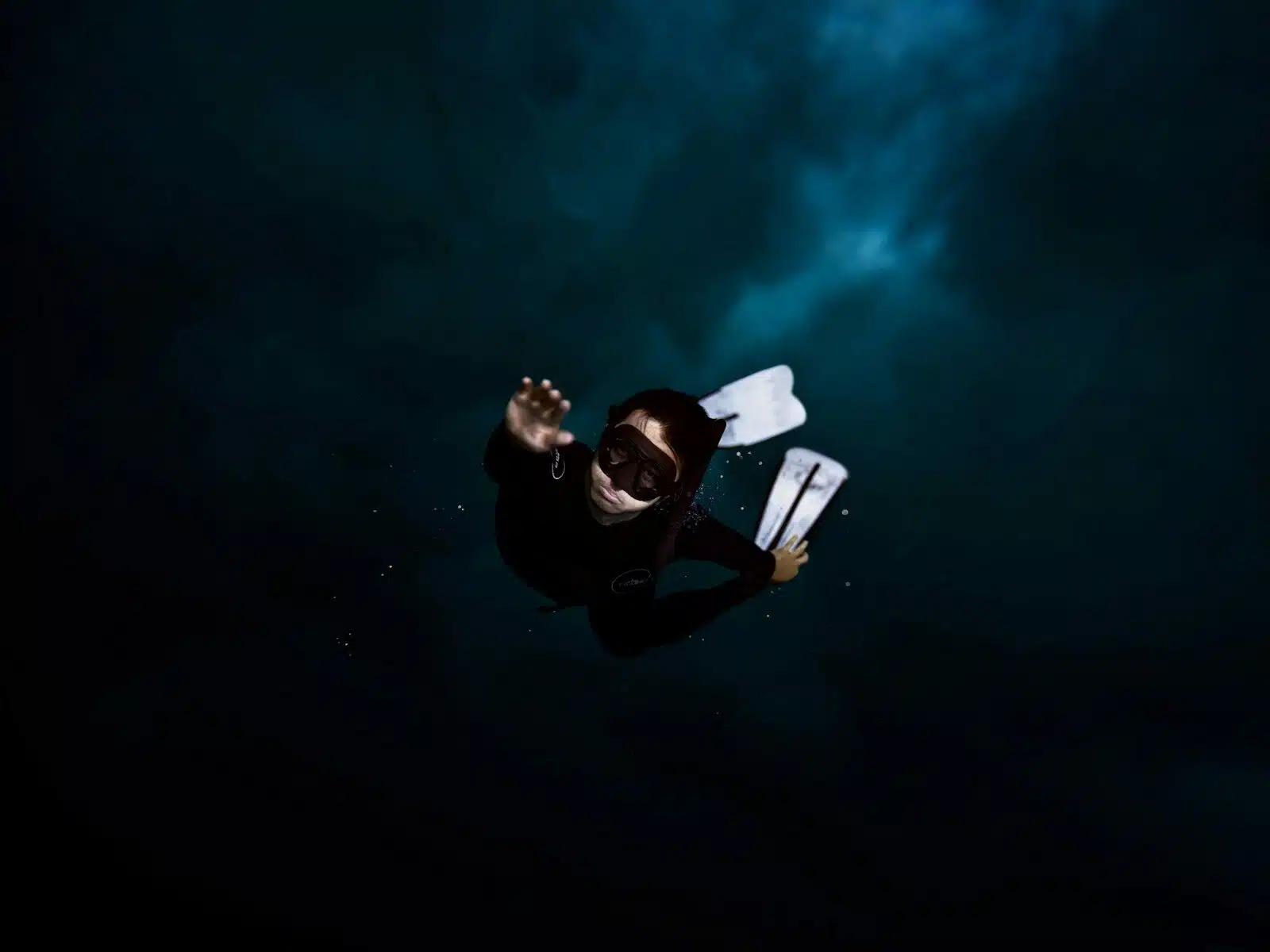 a man in a wet suit holding a surfboard under his arm